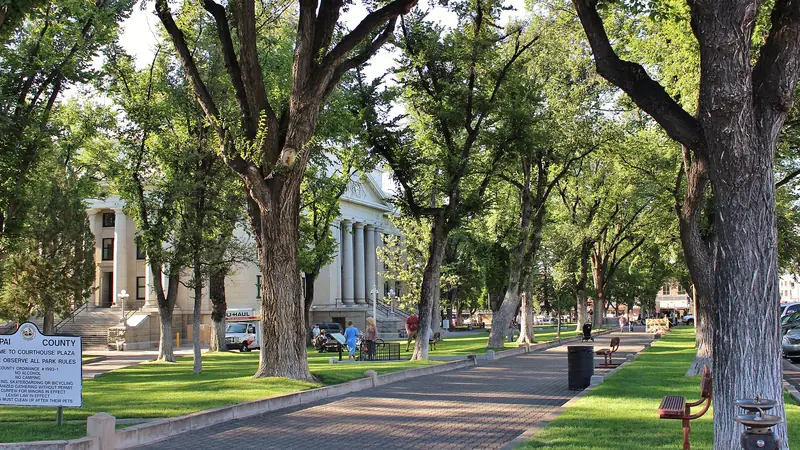 A shaded walkway under tall trees leading across the Courthouse Plaza to the Yavapai County Courthouse