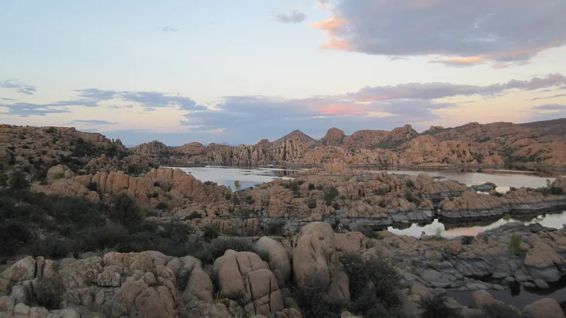 Rounded granite boulders of the Granite Dells with Watson Lake in the distance under a cloudy sky