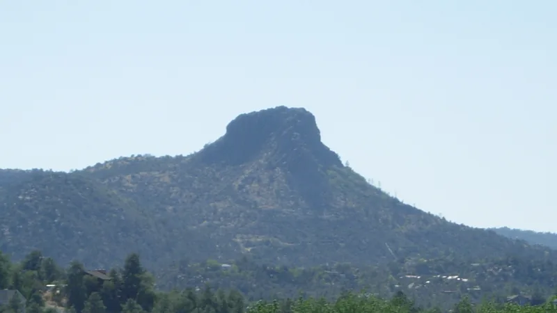 Thumb Butte's rocky summit rising above wooded hills west of Prescott