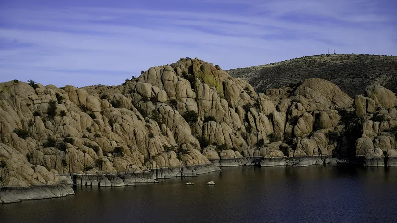 Rounded granite boulders of the Granite Dells rising above the calm water of Watson Lake in evening light, near Prescott, Arizona